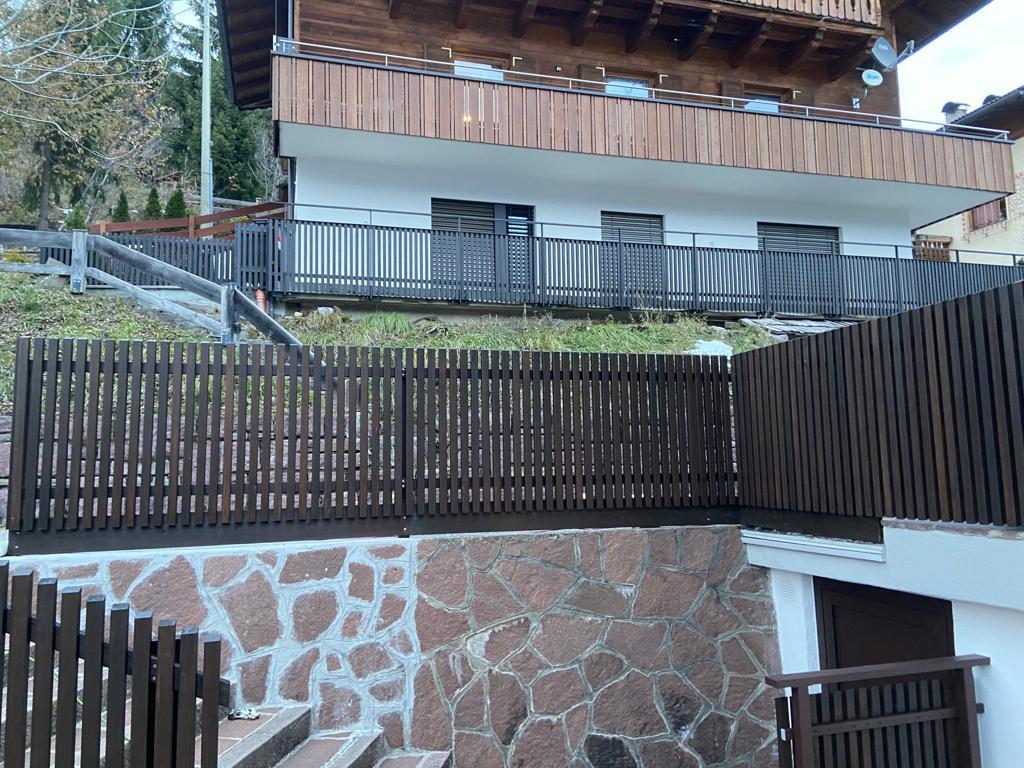 Stäbchenbalkon aus dunkel gestrichener Lärche mit Sockel und Lärchenholz-Handlauf