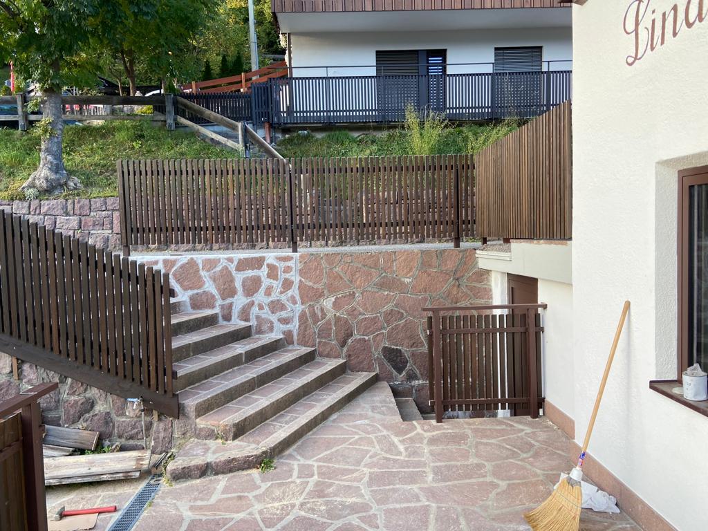 Stäbchenbalkon aus dunkel gestrichener Lärche mit Sockel und Lärchenholz-Handlauf