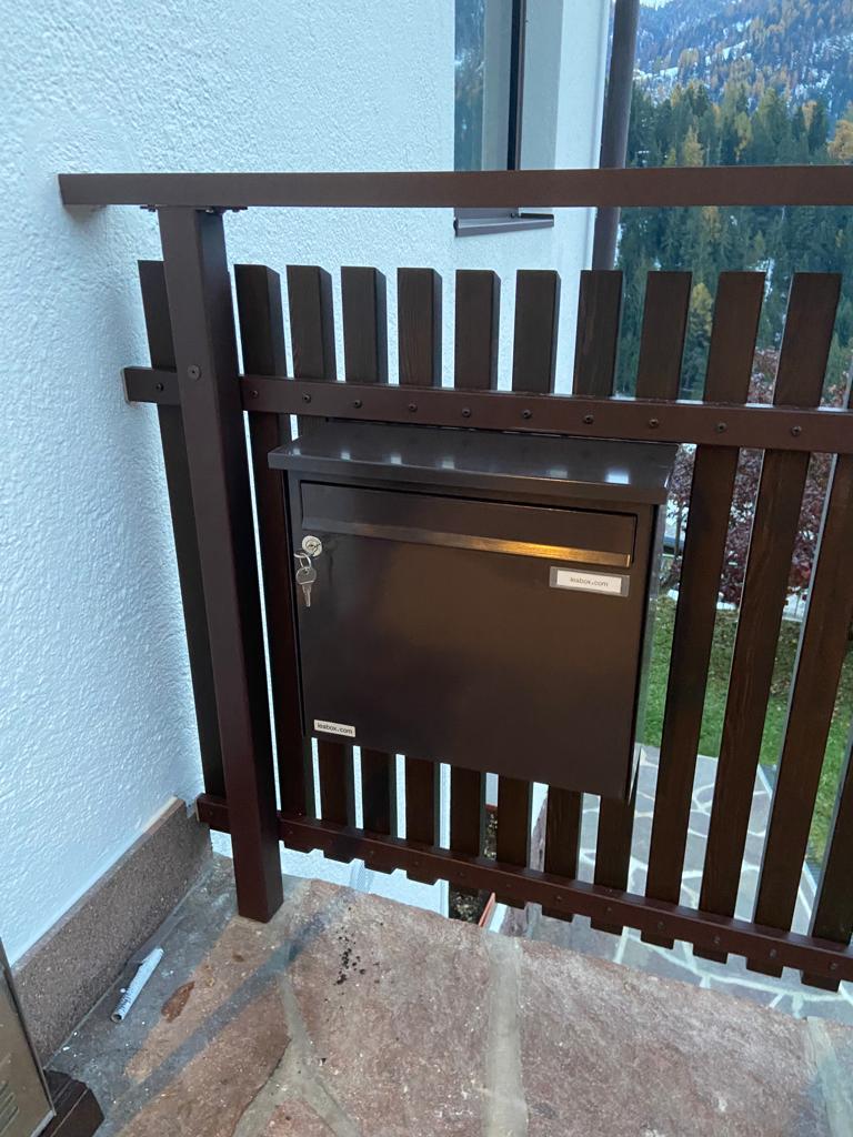Stäbchenbalkon aus dunkel gestrichener Lärche mit Sockel und Lärchenholz-Handlauf