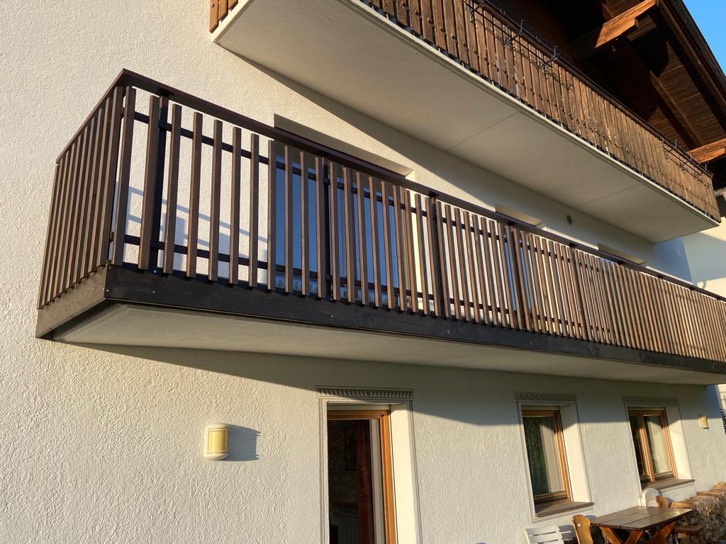 Stäbchenbalkon aus dunkel gestrichener Lärche mit Sockel und Lärchenholz-Handlauf